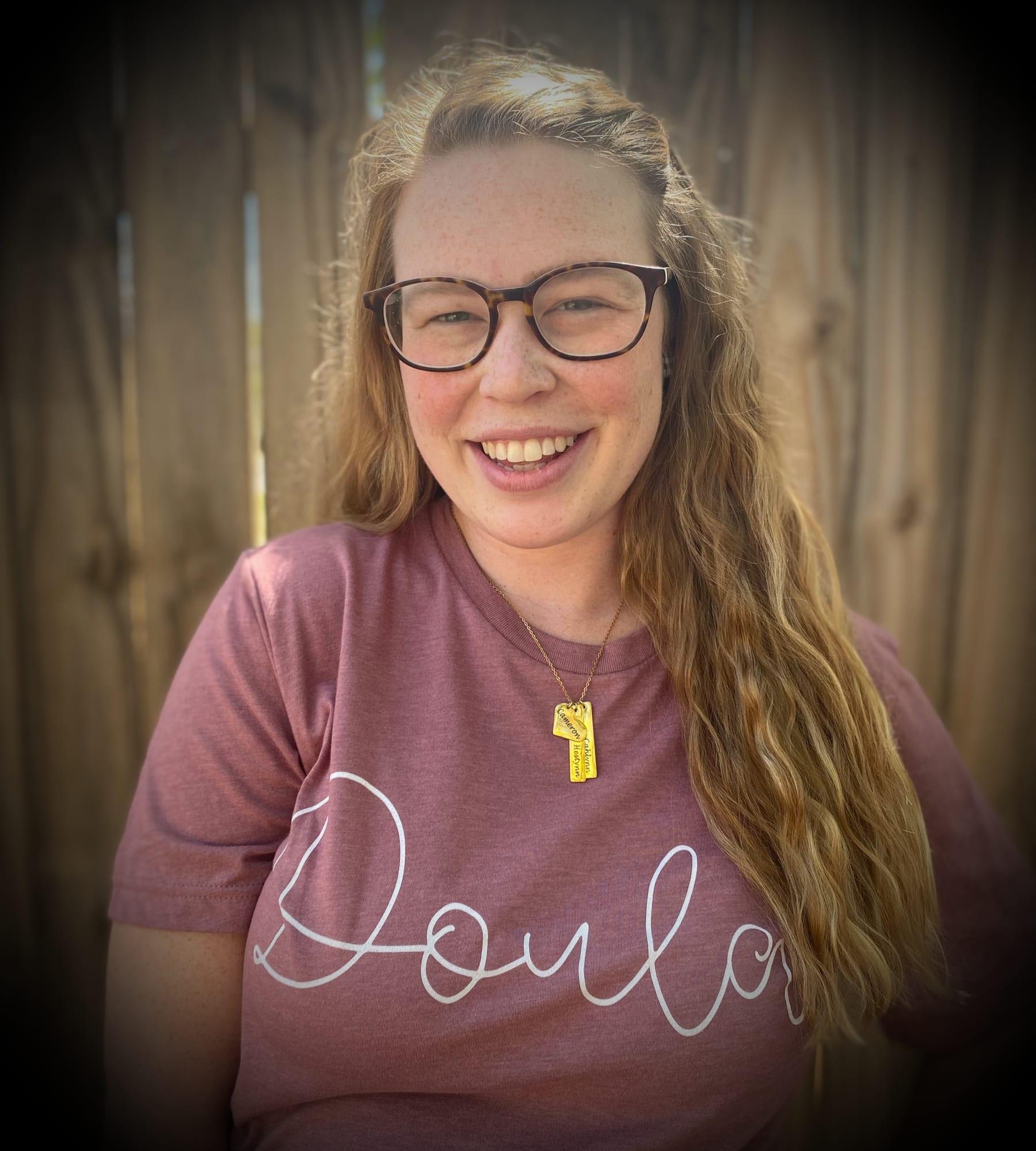 Mackenzie Pineda smiling, wearing a rose 'Doula' t-shirt